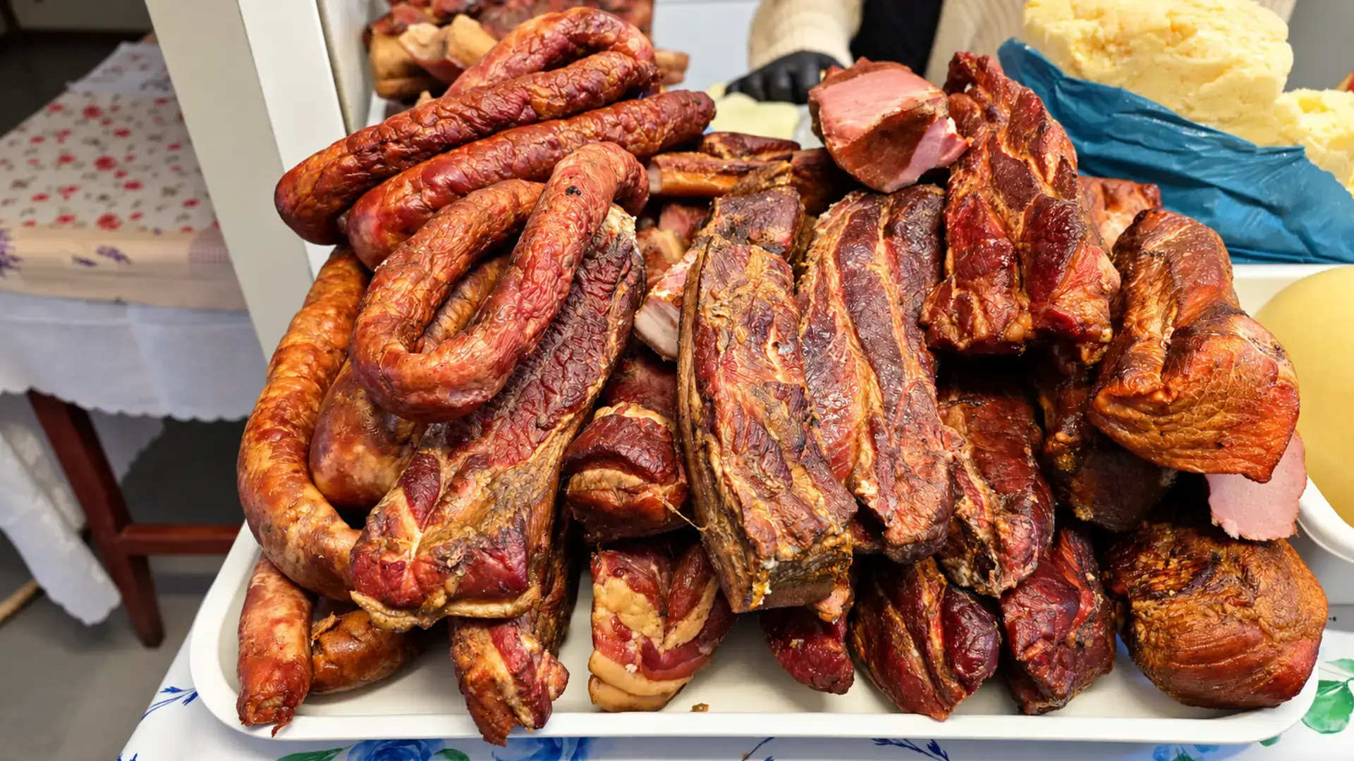 Cârnați de casă și bucăți de carne afumată expuse pe o tavă în Piața Centrală din Piatra-Neamț